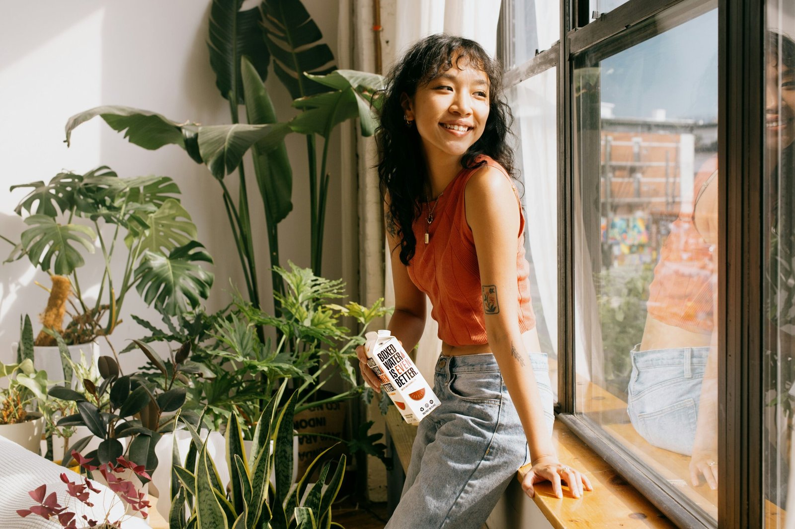 a woman sitting on a window sill next to a potted plant